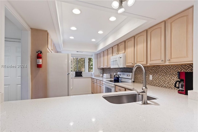 kitchen featuring white appliances, ornamental molding, light brown cabinetry, and a raised ceiling