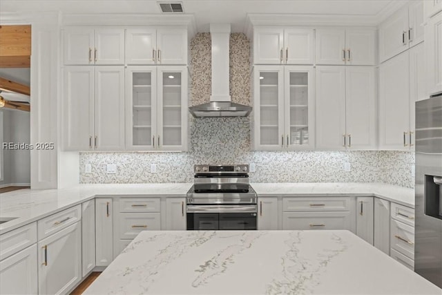 kitchen featuring appliances with stainless steel finishes, wall chimney exhaust hood, and white cabinets