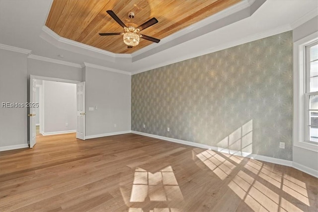 unfurnished room featuring wood ceiling, ornamental molding, a tray ceiling, and light wood-type flooring