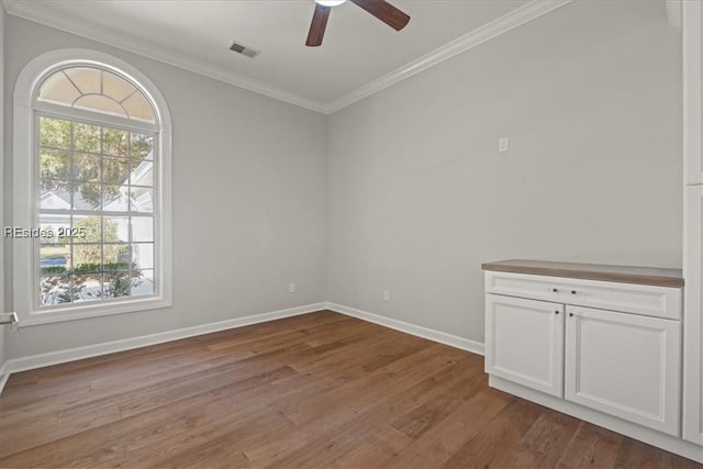 unfurnished room with hardwood / wood-style flooring, ceiling fan, a healthy amount of sunlight, and crown molding