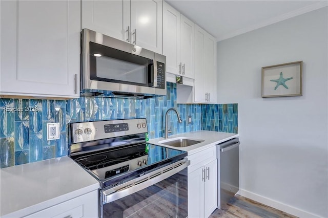 kitchen with sink, white cabinetry, tasteful backsplash, light wood-type flooring, and appliances with stainless steel finishes