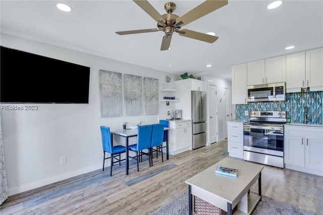 kitchen with tasteful backsplash, white cabinetry, appliances with stainless steel finishes, and light wood-type flooring