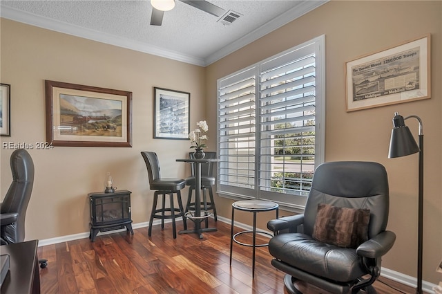 living area featuring dark hardwood / wood-style floors, a wood stove, ceiling fan, crown molding, and a textured ceiling