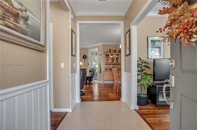 hall featuring light tile patterned flooring, a textured ceiling, and crown molding