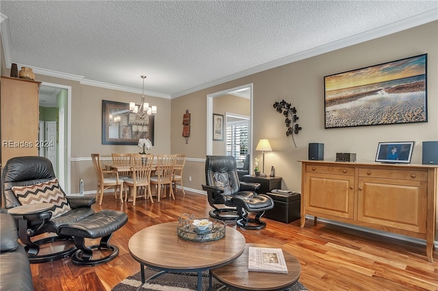 living room featuring ornamental molding, a chandelier, light hardwood / wood-style floors, and a textured ceiling