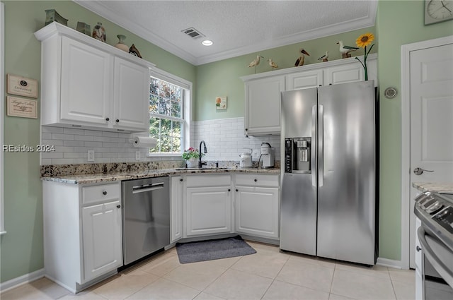 kitchen with sink, appliances with stainless steel finishes, a textured ceiling, white cabinets, and decorative backsplash