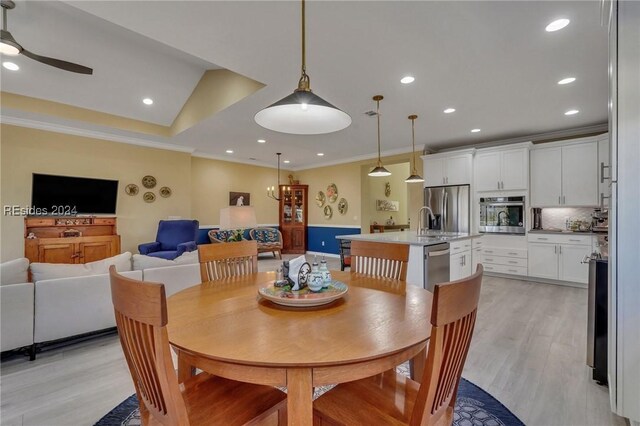 dining space with crown molding, vaulted ceiling, ceiling fan, and light wood-type flooring