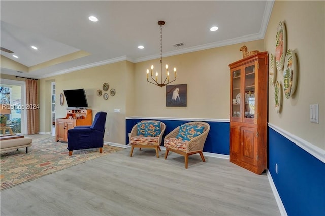 living area featuring ornamental molding, an inviting chandelier, and light wood-type flooring