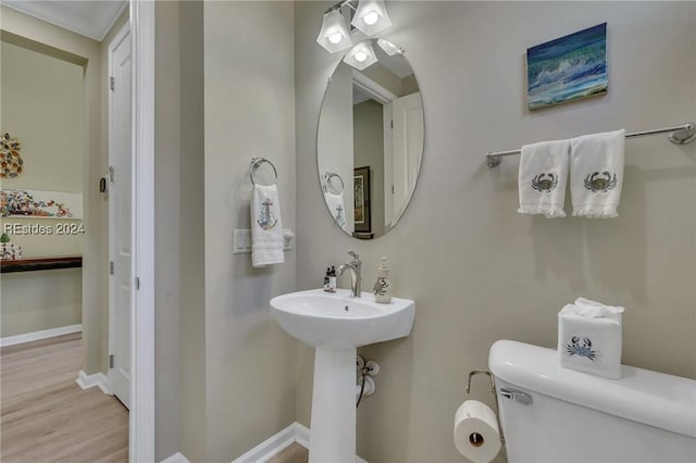 bathroom with crown molding, wood-type flooring, and toilet