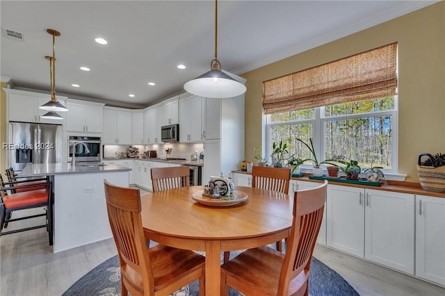 dining room with wine cooler, ornamental molding, and light hardwood / wood-style flooring