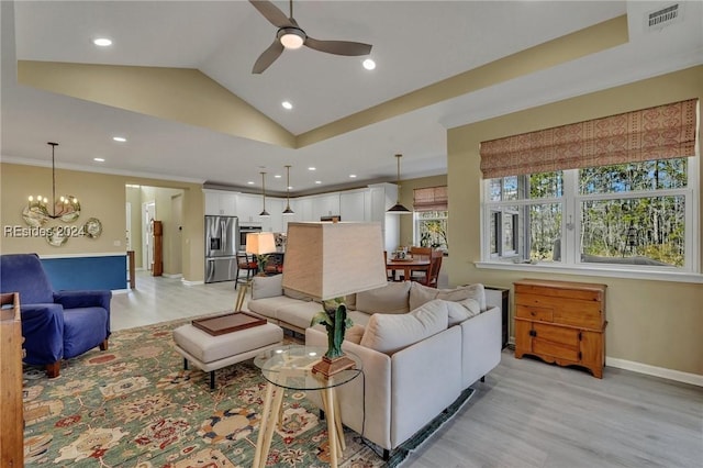 living room featuring lofted ceiling, ceiling fan with notable chandelier, and light hardwood / wood-style flooring