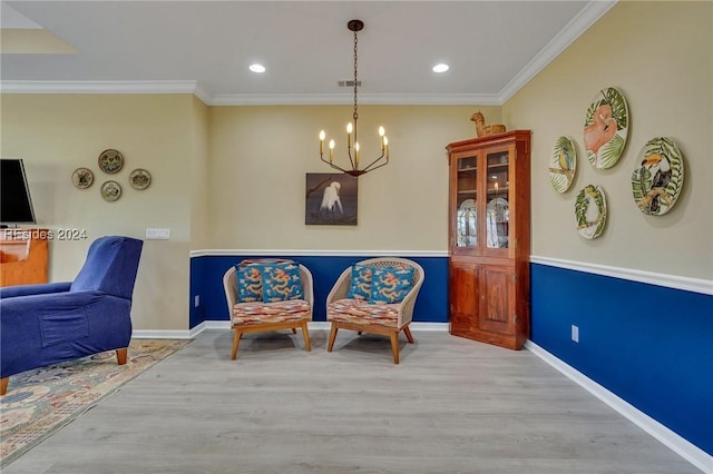 living area with ornamental molding, an inviting chandelier, and light hardwood / wood-style floors