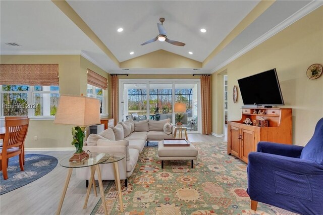 living room with vaulted ceiling, ornamental molding, ceiling fan, and light wood-type flooring