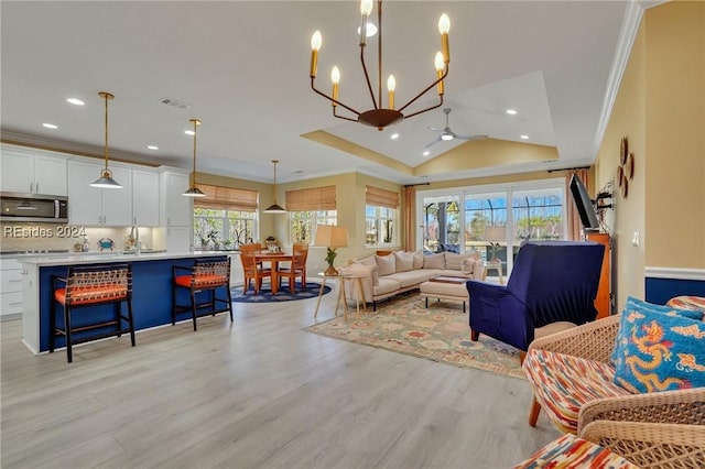 living room with sink, light hardwood / wood-style flooring, ceiling fan, ornamental molding, and vaulted ceiling