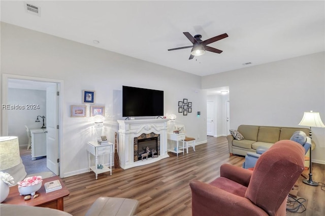 living room with hardwood / wood-style flooring, ceiling fan, and a high end fireplace