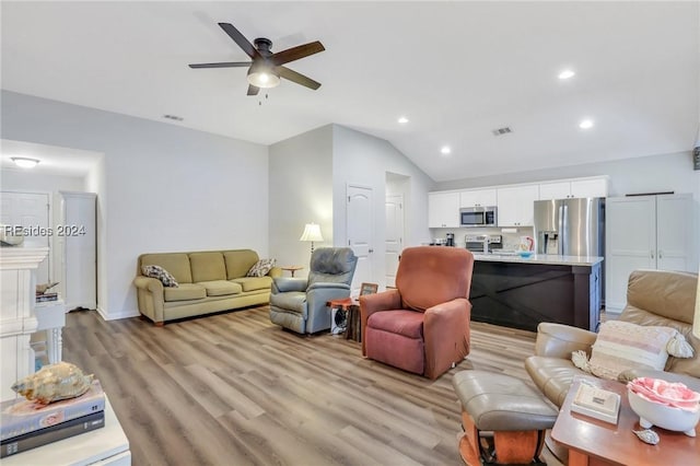 living room with ceiling fan, vaulted ceiling, and light hardwood / wood-style flooring