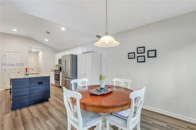 dining space featuring lofted ceiling, sink, and light wood-type flooring