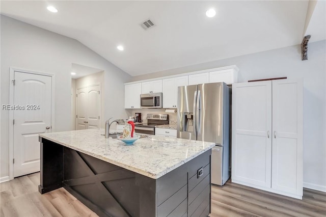 kitchen featuring stainless steel appliances, a center island with sink, white cabinets, and light stone counters