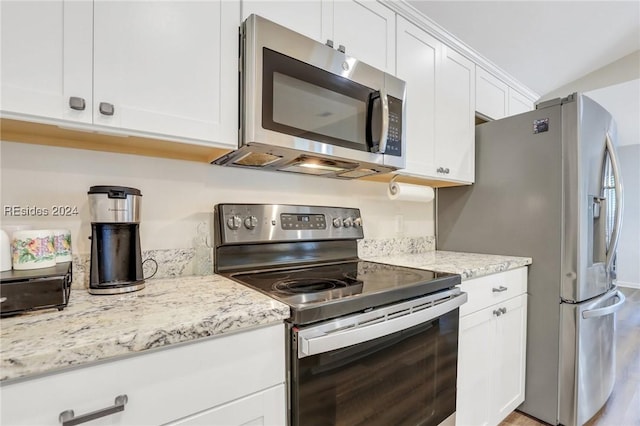 kitchen with white cabinetry, light stone counters, vaulted ceiling, and appliances with stainless steel finishes