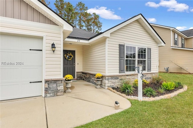 view of exterior entry featuring a garage and a lawn