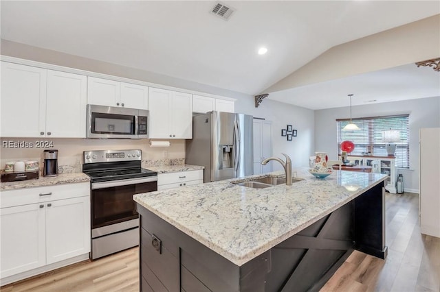 kitchen with appliances with stainless steel finishes, pendant lighting, sink, white cabinets, and a kitchen island with sink