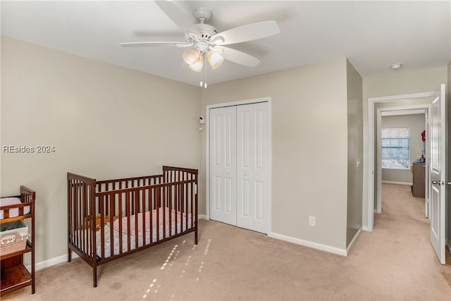 carpeted bedroom featuring a crib, a closet, and ceiling fan