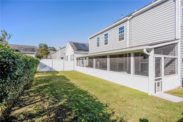 rear view of house featuring a sunroom and a lawn