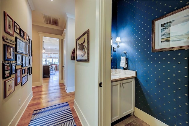 hallway with crown molding and light hardwood / wood-style floors