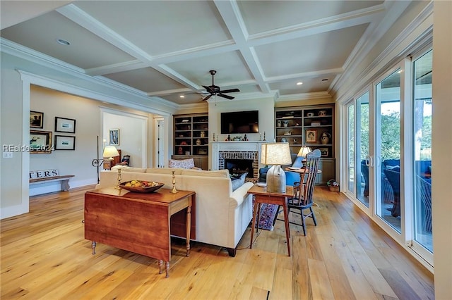 living room with built in features, ceiling fan, coffered ceiling, light hardwood / wood-style floors, and a brick fireplace