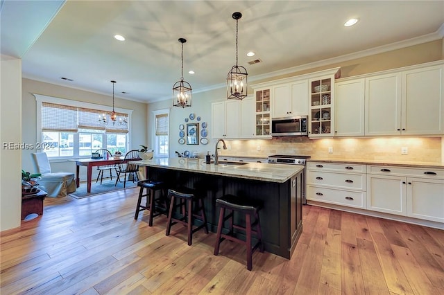 kitchen featuring white cabinetry, sink, a breakfast bar area, light stone countertops, and a center island with sink