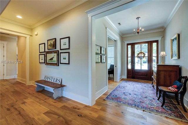 entryway featuring crown molding, a chandelier, and light wood-type flooring