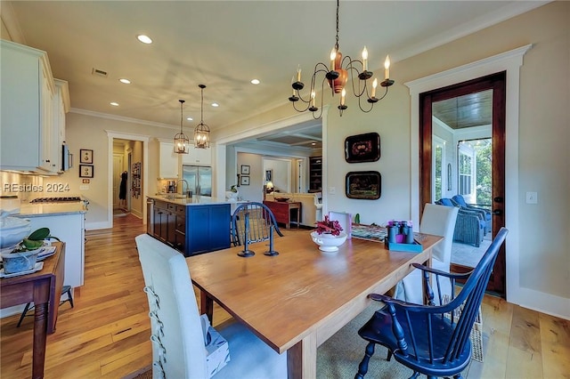 dining space featuring an inviting chandelier, light hardwood / wood-style flooring, and ornamental molding