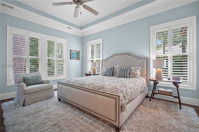 bedroom with hardwood / wood-style floors, a tray ceiling, ornamental molding, and ceiling fan