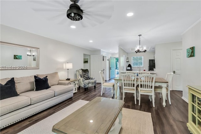 living room with dark wood-type flooring, ornamental molding, and a chandelier