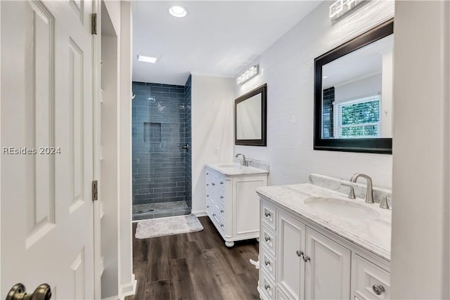 bathroom with hardwood / wood-style flooring, vanity, and tiled shower