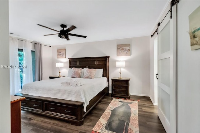 bedroom with dark hardwood / wood-style flooring, a barn door, and ceiling fan