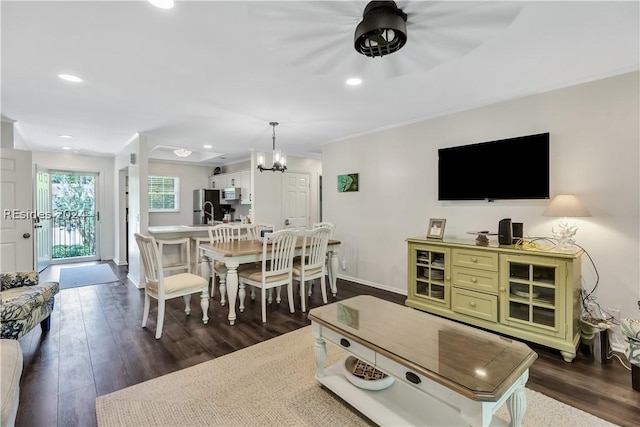 living room with dark wood-type flooring, crown molding, and a notable chandelier