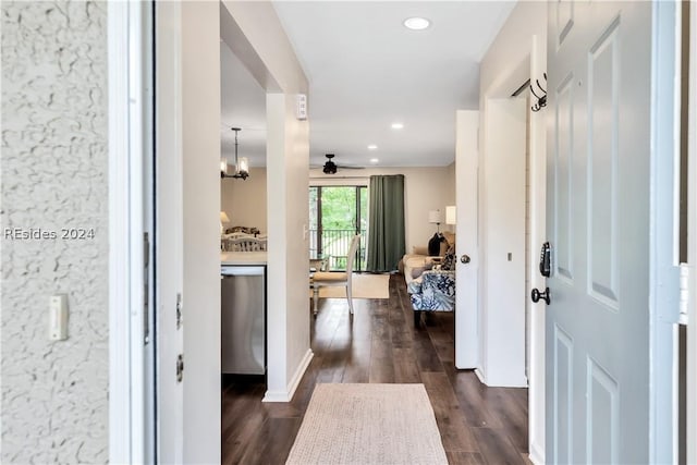 hallway with dark wood-type flooring and an inviting chandelier