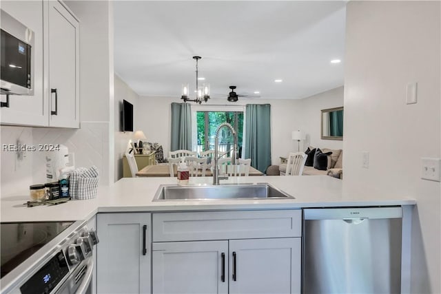 kitchen featuring appliances with stainless steel finishes, sink, kitchen peninsula, and decorative backsplash