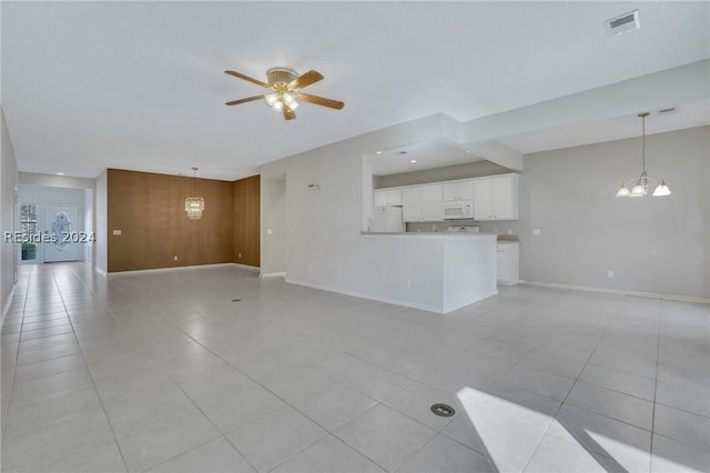 unfurnished living room with light tile patterned floors, ceiling fan with notable chandelier, and wood walls