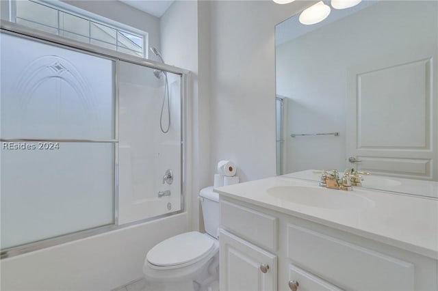 full bathroom with vanity, enclosed tub / shower combo, and toilet