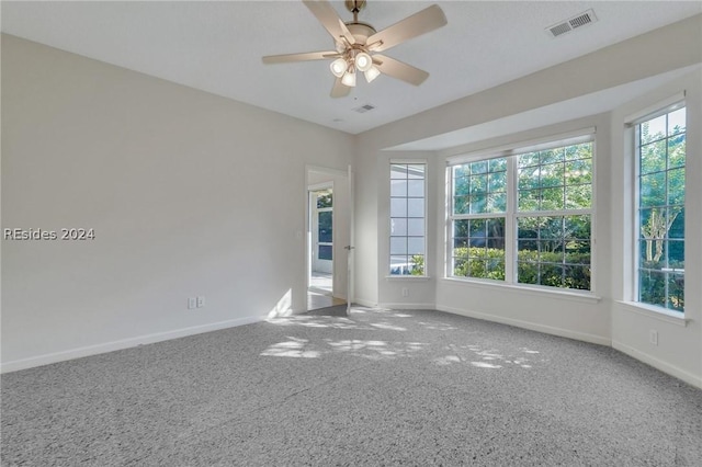 carpeted spare room with plenty of natural light and ceiling fan