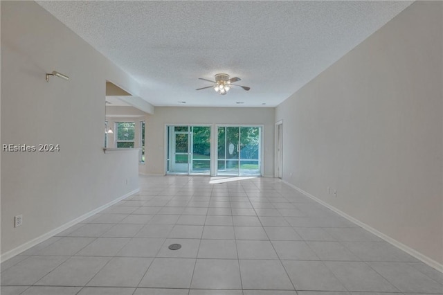 tiled empty room with ceiling fan and a textured ceiling