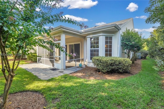 rear view of house with a patio area, a sunroom, and a lawn