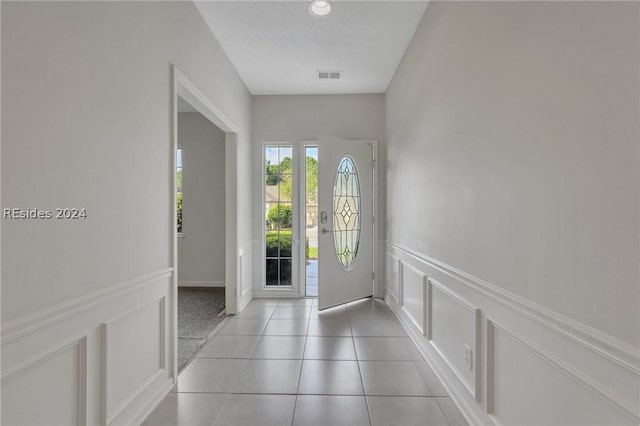 entryway with light tile patterned floors and a textured ceiling