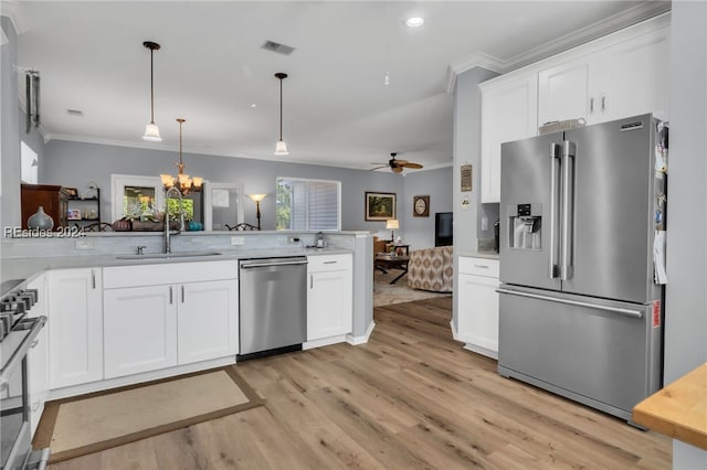 kitchen with appliances with stainless steel finishes, white cabinetry, hanging light fixtures, plenty of natural light, and kitchen peninsula