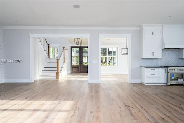 unfurnished living room with ornamental molding, light hardwood / wood-style floors, and french doors