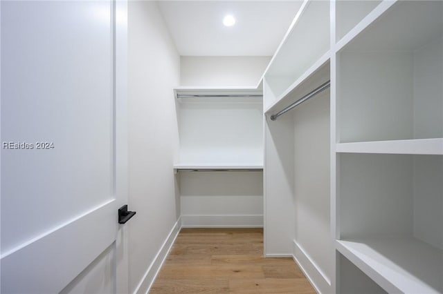 walk in closet with light hardwood / wood-style floors