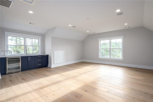 interior space featuring wine cooler, lofted ceiling, and light hardwood / wood-style flooring