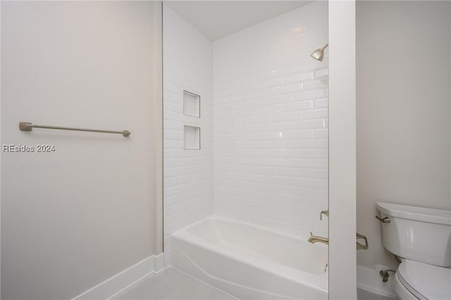 bathroom with tile patterned flooring, tub / shower combination, and toilet